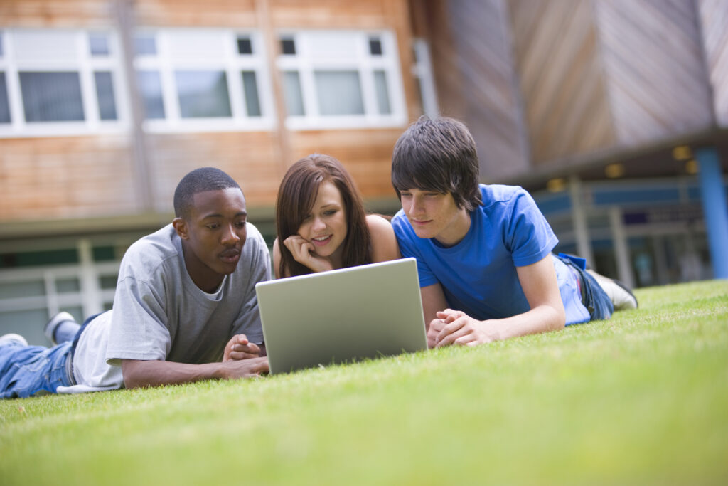 College students using laptop on campus lawn